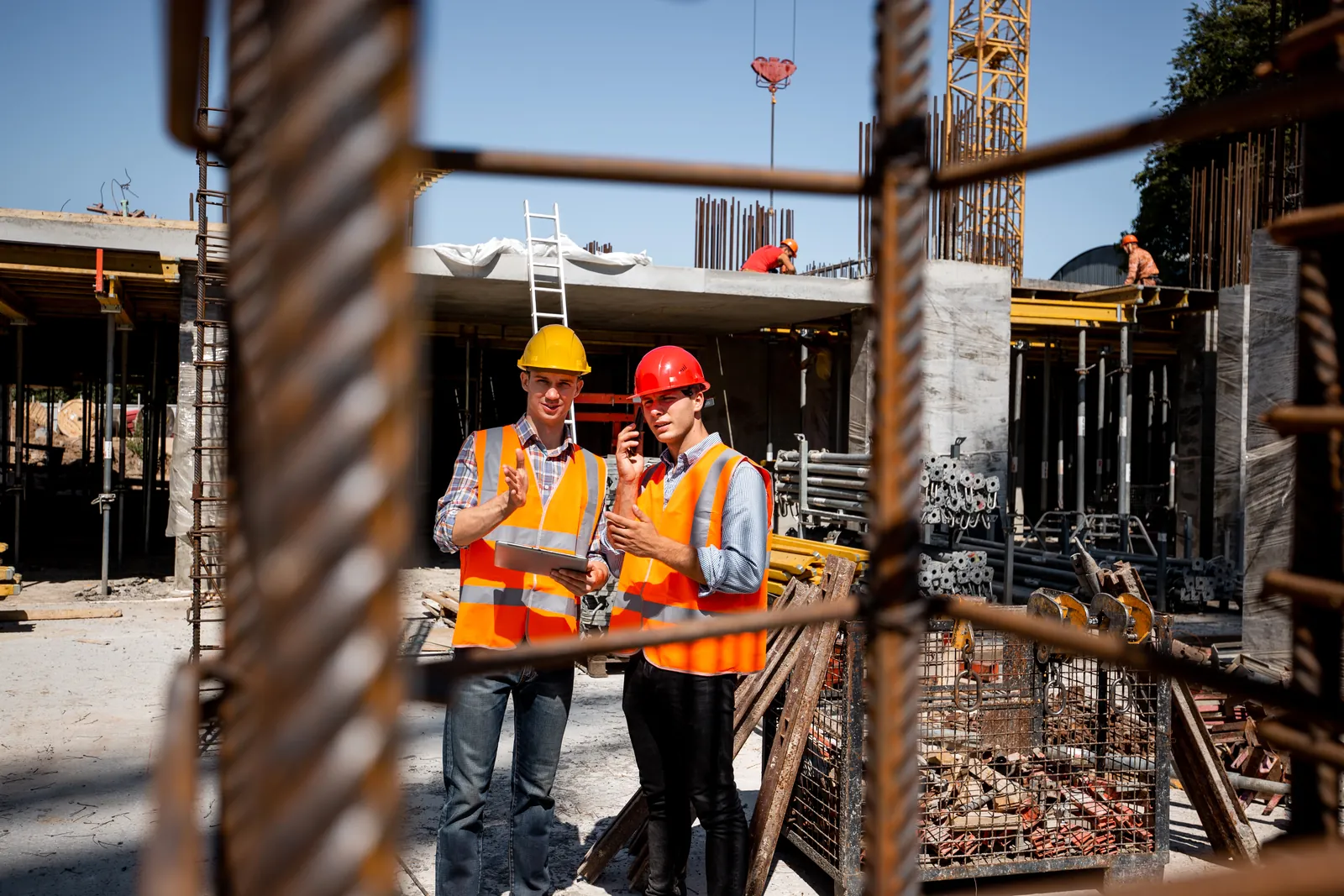 Two site workers in hard hats and hi-vis reviewing plans on a construction site