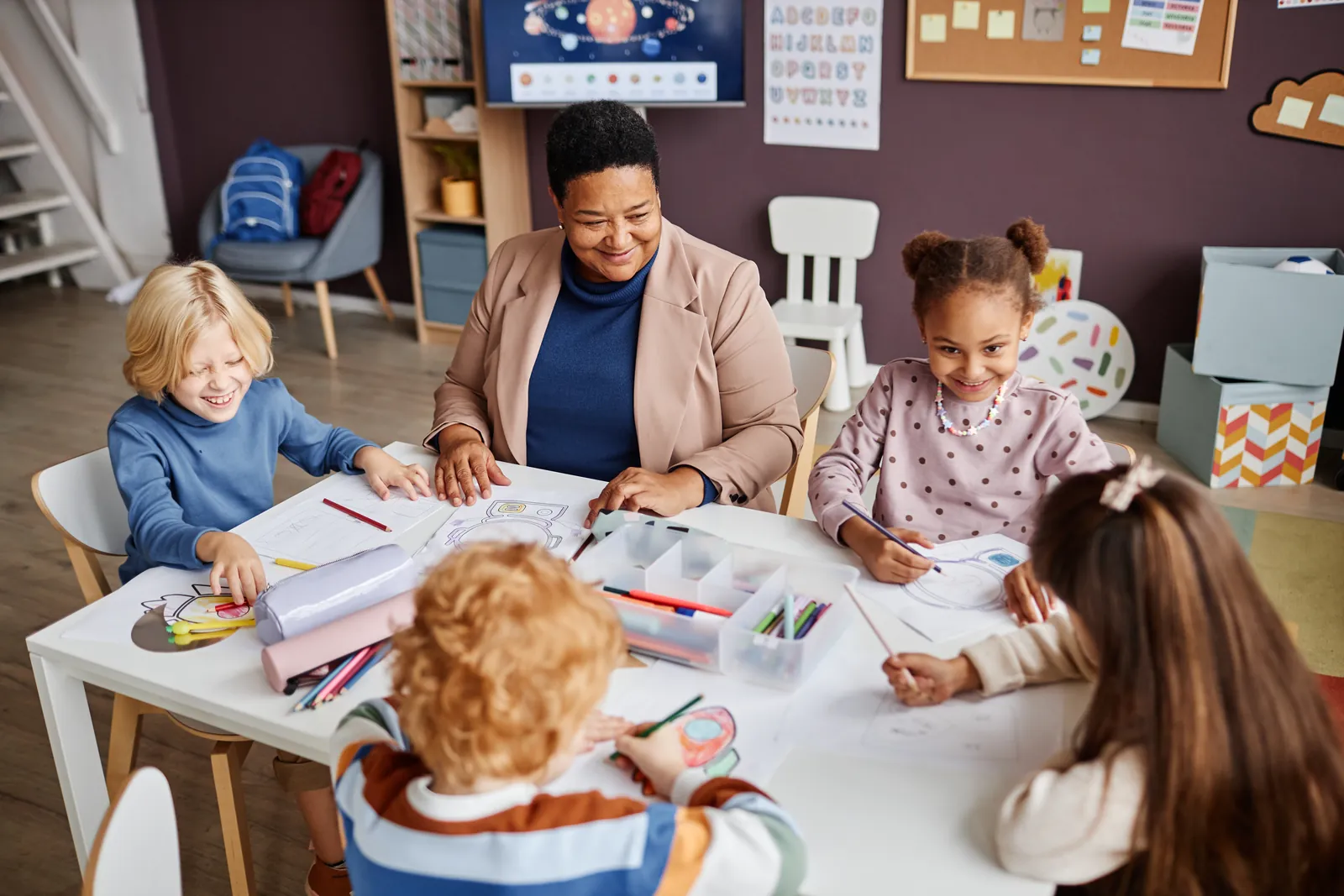 An early years practitioner working with young children at a nursery table
