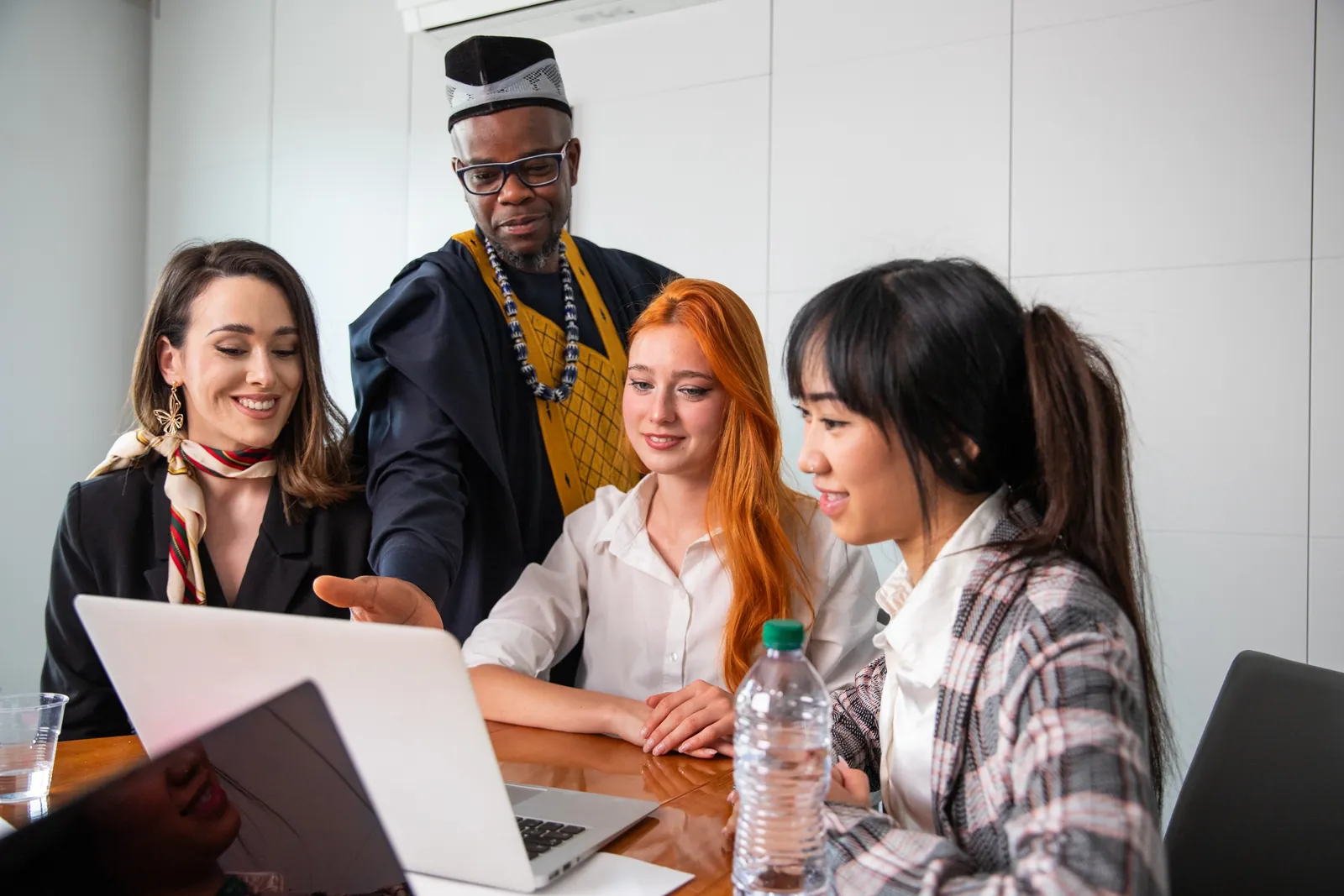 An international group reviewing work together on a laptop